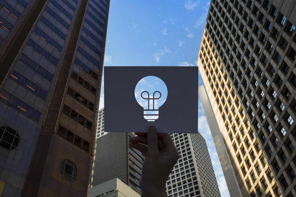Mão segurando papel recortado em forma de lâmpada simbolizando uma ideia