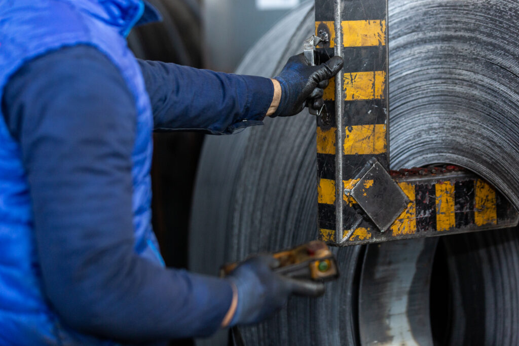 Trabalhador com duas luvas manuseando metal
